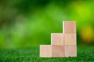 Stacking blank wooden cubes on green background with copy space for input wording and infographic icon. Empty brown wooden object block for symbol icon put technology, zero gravity, business concept. photo