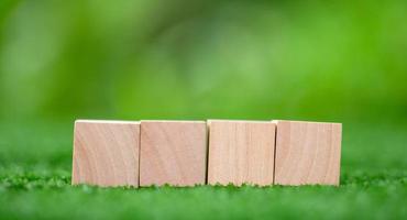 Stacking blank wooden cubes on green background with copy space for input wording and infographic icon. Empty brown wooden object block for symbol icon put technology, zero gravity, business concept. photo