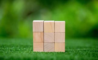 Stacking blank wooden cubes on green background with copy space for input wording and infographic icon. Empty brown wooden object block for symbol icon put technology, zero gravity, business concept. photo