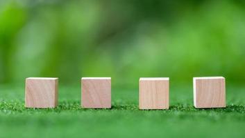 Stacking blank wooden cubes on green background with copy space for input wording and infographic icon. Empty brown wooden object block for symbol icon put technology, zero gravity, business concept. photo