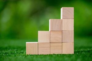 Stacking blank wooden cubes on green background with copy space for input wording and infographic icon. Empty brown wooden object block for symbol icon put technology, zero gravity, business concept. photo