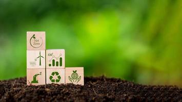 Net zero and carbon neutral concept. Net zero greenhouse gas emissions target. Climate neutral long term strategy. Wooden cubes with green net zero icon and green conserve icon on nature background. photo