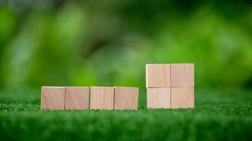 Stacking blank wooden cubes on green background with copy space for input wording and infographic icon. Empty brown wooden object block for symbol icon put technology, zero gravity, business concept. photo