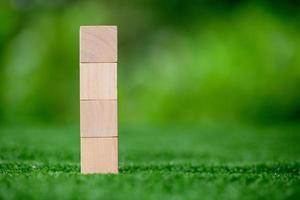 Stacking blank wooden cubes on green background with copy space for input wording and infographic icon. Empty brown wooden object block for symbol icon put technology, zero gravity, business concept. photo