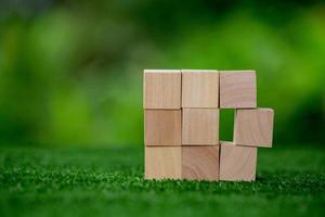 Stacking blank wooden cubes on green background with copy space for input wording and infographic icon. Empty brown wooden object block for symbol icon put technology, zero gravity, business concept. photo