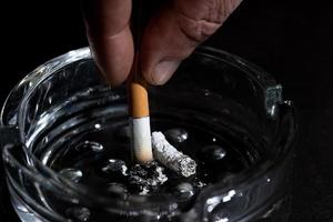Ashtray and smoking cigarette on black background photo