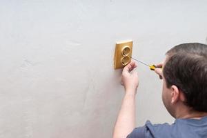 Electrician replacing socket in room photo