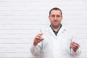 Handsome middle age man wearing doctor uniform holding syringe photo