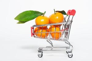 fresh mangerines and a shopping cart on a white background photo