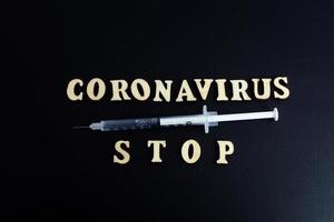 una jeringa con una dosis de medicamento o vacuna sobre un fondo negro con un espacio para las vacunas de texto contra el coronavirus de la gripe foto