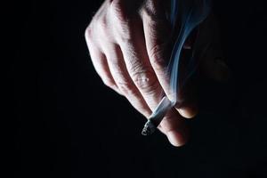 A Cropped of man hand holding cigarette black background photo