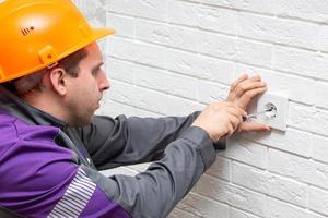 Electrician replacing socket in room photo