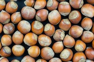 Hazelnuts on a black background. Fresh hazelnut harvest is scattered on black table. photo