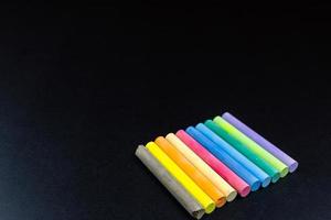 Multicoloured chalk on blackboard background photo