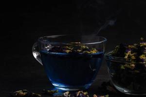 Butterfly pea flower tea in a clear glass on a black background. photo