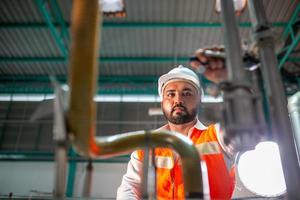 professional technician engineer with safety hard hat working to maintenance construction equipment in industrial factory, worker is checking or repair the machine. photo