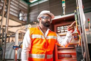 Asian engineer worker wearing safety uniform control operating  machine and turn on switch in industry factory. photo