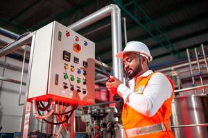 Professional engineers with helmets work to maintain industrial construction equipment, workers are inspecting or repairing machines  with radio. photo