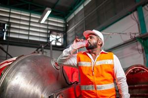 Professional engineers with helmets work to maintain industrial construction equipment. The worker is thirsty and drink refreshing water. photo