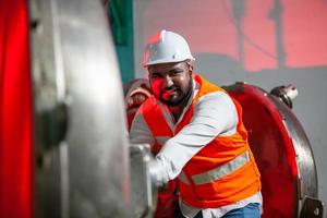 professional technician engineer with safety hard hat working to maintenance construction equipment in industrial factory, worker is checking or repair the machine. photo