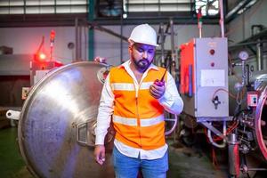 Professional engineers with helmets work to maintain industrial construction equipment, workers are inspecting or repairing machines  with radio. photo
