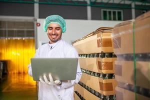 trabajador con computadora portátil está revisando el producto en la línea de producción en la fábrica de bebidas. el fabricante comprueba la calidad de la industria alimentaria. foto