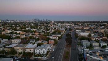 vista de la puesta de sol caliente de los angeles con palmeras y el centro de la ciudad en el fondo. foto