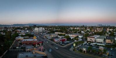 vista de la puesta de sol caliente de los angeles con palmeras y el centro de la ciudad en el fondo. foto