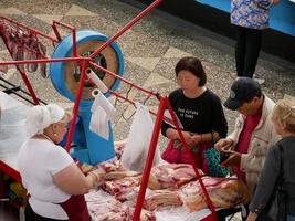 Almaty, Kazakhstan, 2019 - People in the meat section of the famous Green Bazaar of Almaty, Kazakhstan, with goods on display. photo