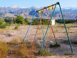 en un parque infantil vacío en cholpon ata, kirguistán, con montañas al fondo foto