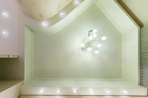 techo tensado de forma blanca y compleja con lámparas halógenas y construcción de paneles de yeso en una habitación vacía en un apartamento o casa. techo suspendido . foto