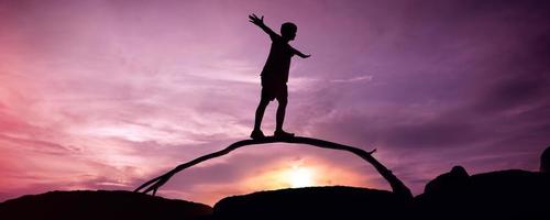 Work Life Balance Concept. Silhouette of Person Balancing Body to Crossing tree branch.Twilight Scenery on Beach or Moutain. Balancing Body, Mind, Soul and Spirit. Mental Meditation Practice photo