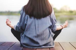 mujer joven practica yoga al aire libre. sentado en posición de loto. concepto de vida desconectada y salud mental. postura sukhasana y meditación foto