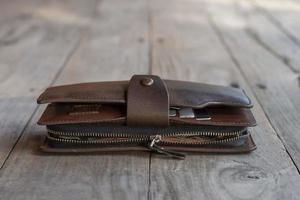 Broken zipper of the wallet made of leather on wooden table. photo