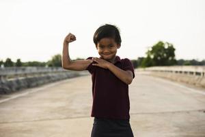 A boy showing his arm muscles a picture of an Asian boy. photo