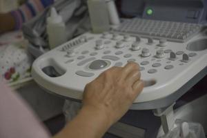 ultrasound machine There is a hand on the control panel. Medical staff perform ultrasound of pregnant women. photo