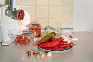 cooking adjika from hot pepper and garlic ground in a meat grinder. preparations for the winter. folk remedy for flu and colds photo