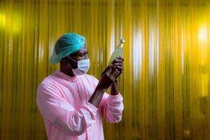 Worker of science in bottle beverage factory wearing safety hat posing show work to check quality of Basil seed produce on conveyer belt before distribution to market business. photo