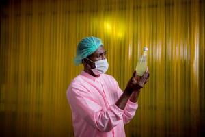 Worker of science in bottle beverage factory wearing safety hat posing show work to check quality of Basil seed produce on conveyer belt before distribution to market business. photo