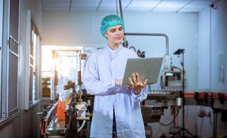 Worker of science in bottle beverage factory wearing safety hat posing show work to check quality of Basil seed produce on conveyer belt before distribution to market business. photo