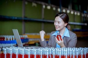 Worker of science in bottle beverage factory wearing safety hat posing show work to check quality of Basil seed produce on conveyer belt before distribution to market business. photo