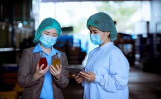 Worker of science in bottle beverage factory wearing safety hat posing show work to check quality of Basil seed produce on conveyer belt before distribution to market business. photo