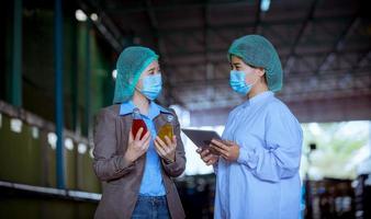 trabajador científico en una fábrica de bebidas embotelladas con sombrero de seguridad posando para comprobar la calidad de los productos de semillas de albahaca en la cinta transportadora antes de su distribución al negocio del mercado. foto