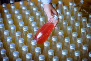 botellas de la cinta transportadora de la fábrica de bebidas de semillas de albahaca con botellas para jugo o agua para su distribución en el negocio. foto