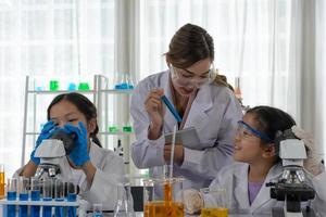 Children Using Microscope to Learn Microbiology and Science in Laboratory with Teacher photo