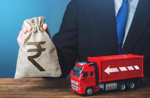 Businessman with indian rupee money bag and truck. Good salaries for drivers. Rising prices, global containers shortage crisis. High income of the transport business and the transport of goods. photo