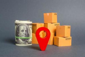 Red navigational location designator, cardboard boxes and a Roll bundle of dollars. Business and commerce. Local economy and manufacture. Production and export of products, goods. Globalization photo