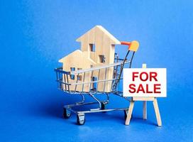 Houses in a shopping cart and an easel sign labeled for sale. Buying and selling real estate, hot offers and property valuation. Smart investments. Discounts and great offers, cheap loans for purchase photo