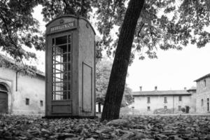 Unrelated english Phone box in an old italian village Concept of communication and unrelated object photo