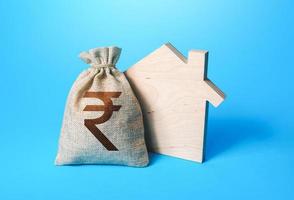 House silhouette and a indian rupee money bag. Mortgage loan. Realtor services. House project development. Rental business. Property appraisal. Home purchase, investment in real estate construction. photo